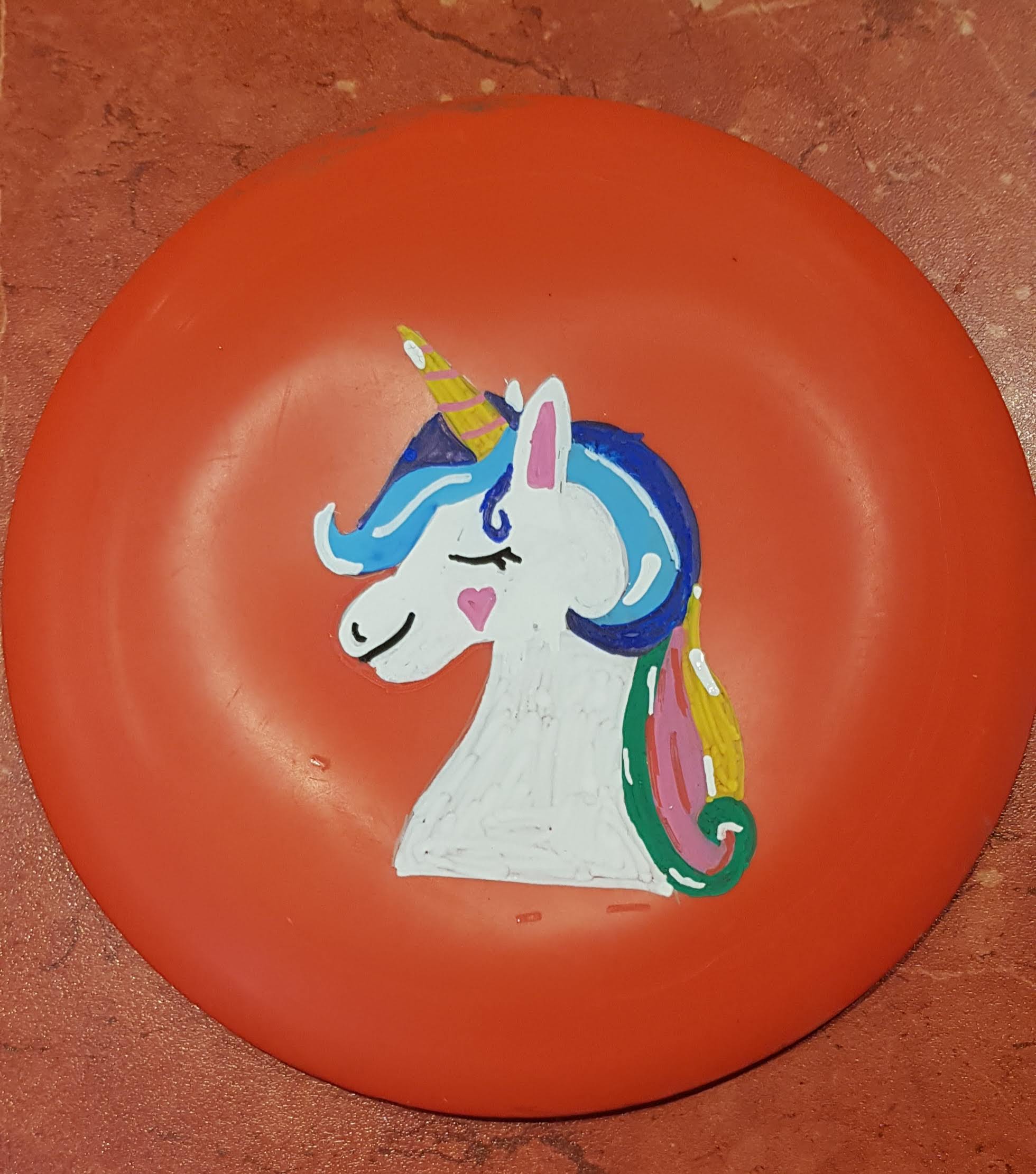 A Drawing of a Unicorn done in Posca Marker on a frisbee